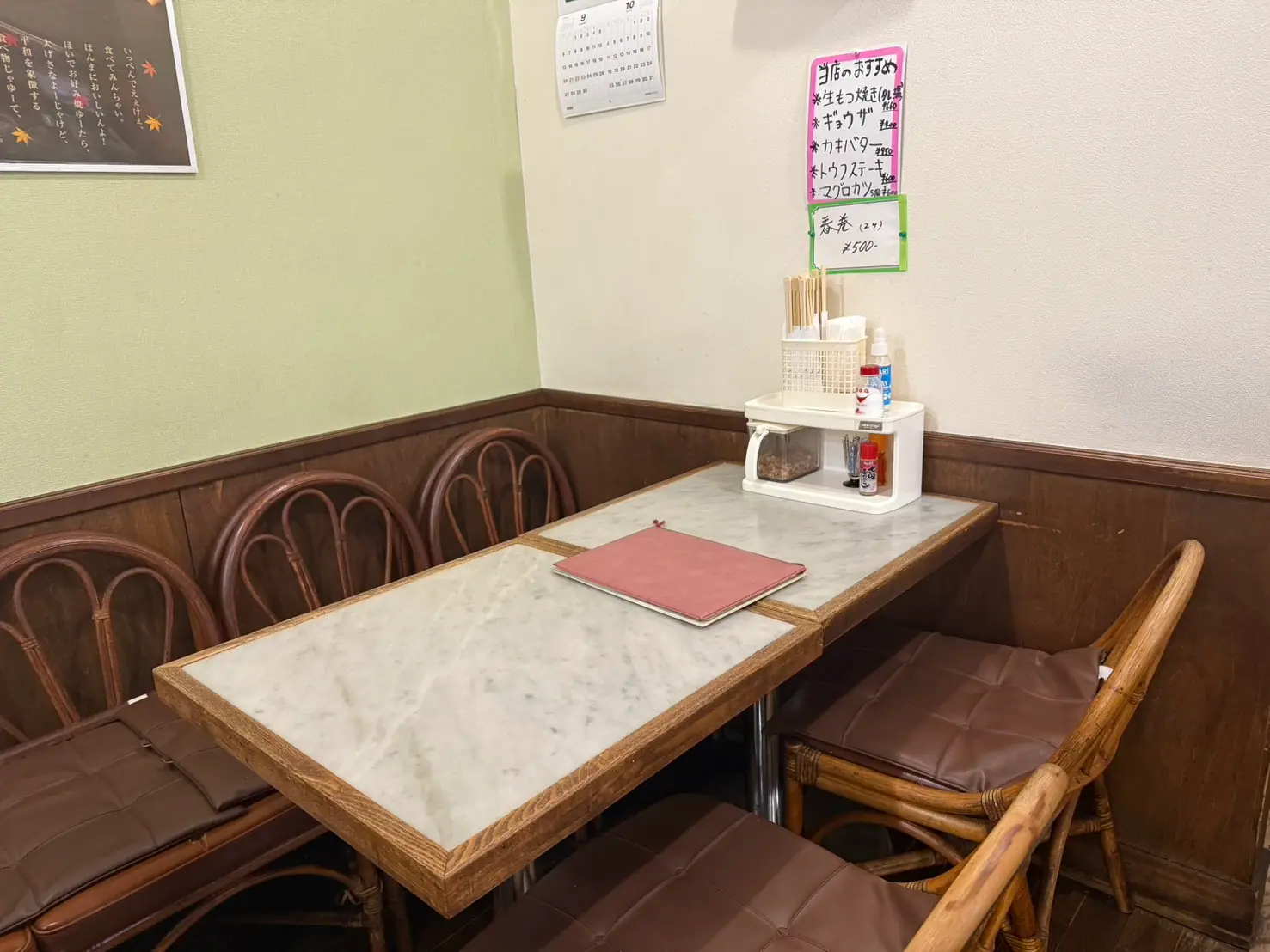 壁際のテーブル席。手書きのおすすめメニューが貼られている